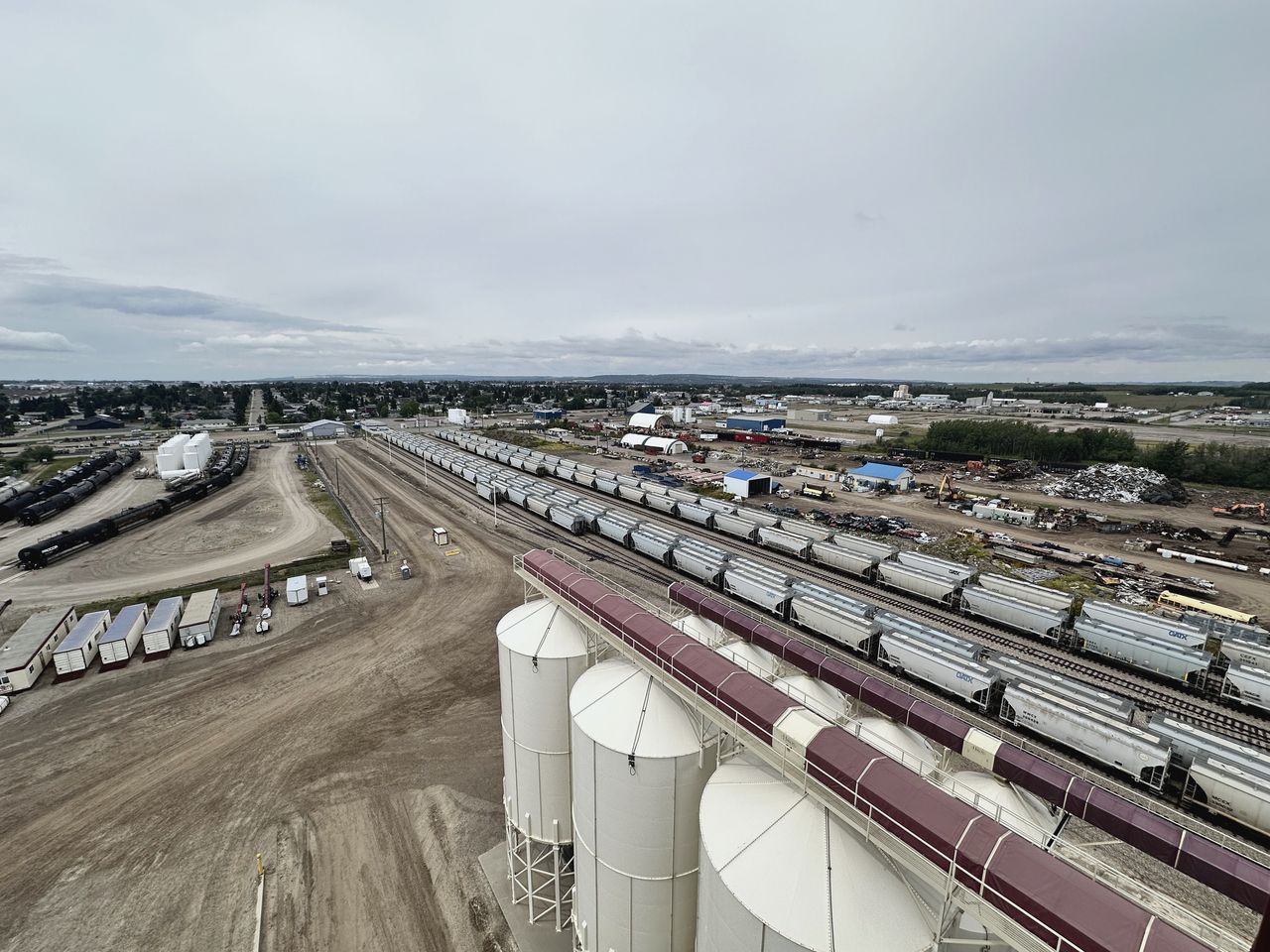 Elevated view of a rail yard with strings of hopper cars and storage silos